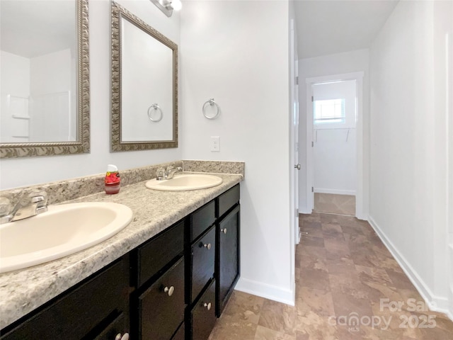 bathroom featuring double vanity, baseboards, and a sink