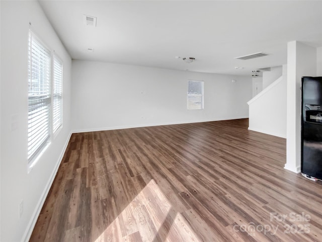 unfurnished living room featuring visible vents, baseboards, and wood finished floors