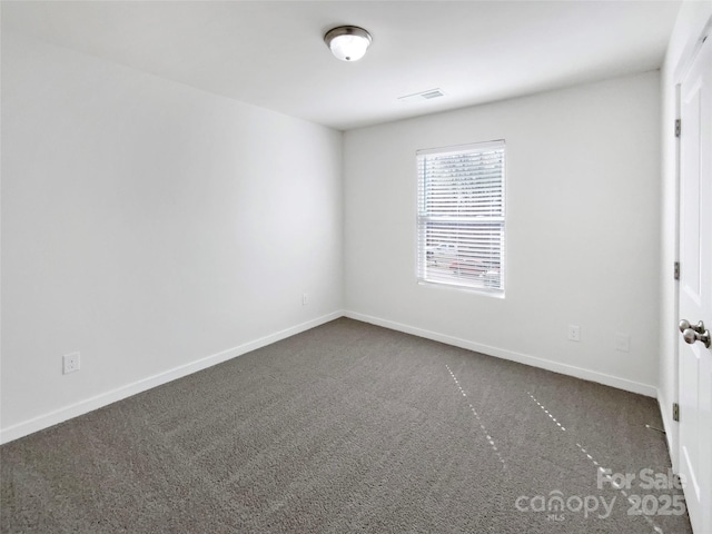 unfurnished room featuring dark colored carpet, visible vents, and baseboards