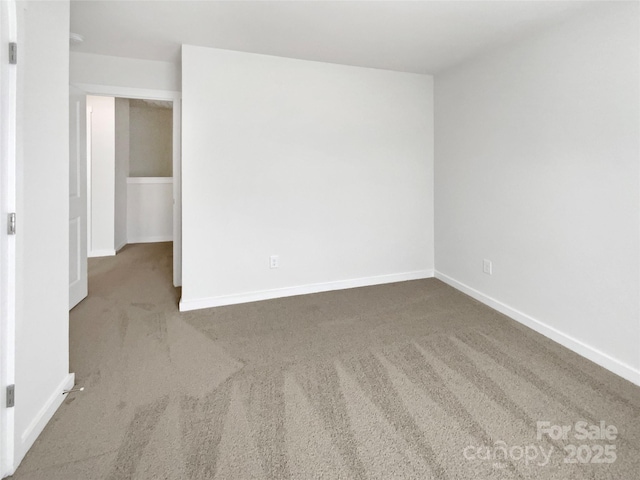 unfurnished room featuring carpet and baseboards