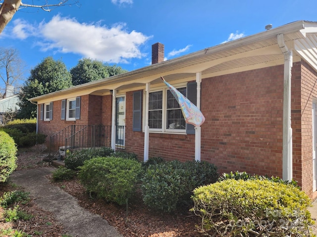 exterior space with brick siding and a chimney