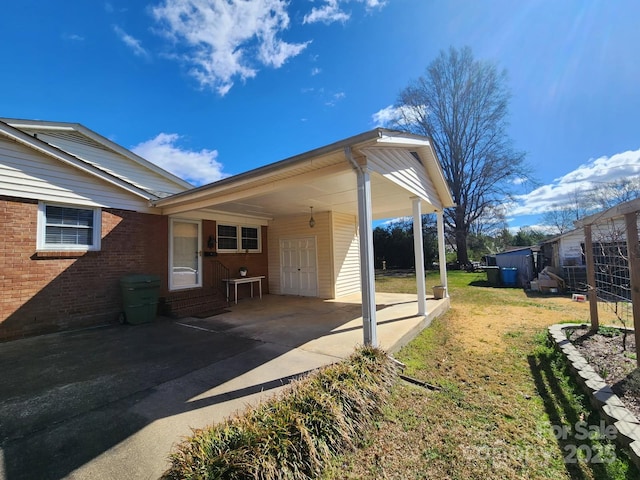 view of property exterior with an attached carport, driveway, a lawn, and brick siding