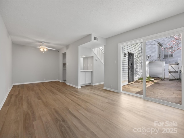 unfurnished living room featuring visible vents, ceiling fan, a textured ceiling, wood finished floors, and baseboards