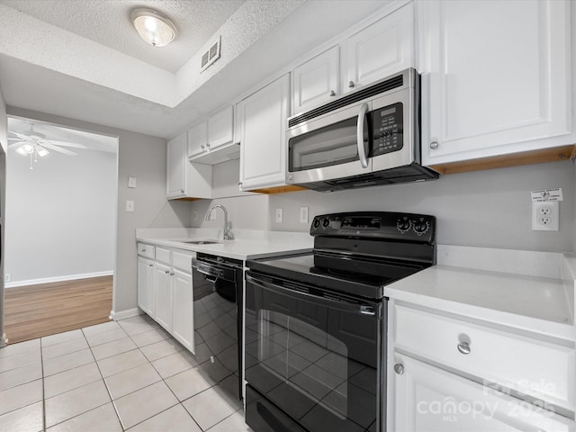 kitchen with black appliances, visible vents, white cabinets, and a sink