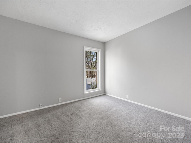 spare room with carpet floors, a textured ceiling, and baseboards