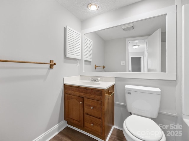 bathroom with baseboards, toilet, wood finished floors, a textured ceiling, and vanity