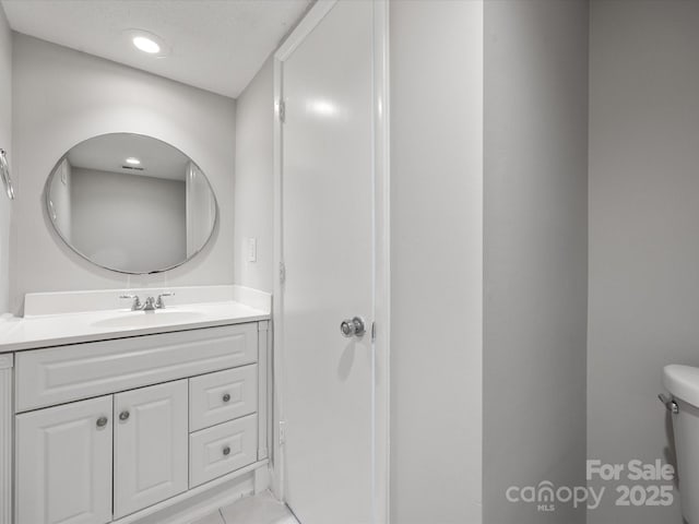 bathroom featuring a textured ceiling, vanity, and toilet