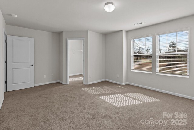 carpeted empty room featuring baseboards and visible vents