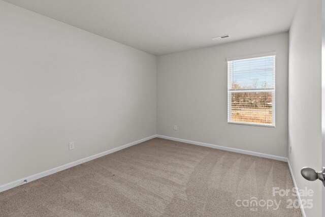 carpeted empty room featuring visible vents and baseboards