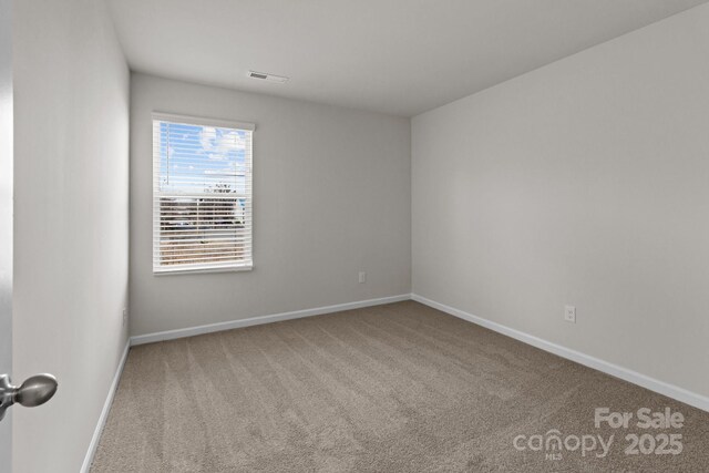 spare room featuring carpet flooring, visible vents, and baseboards