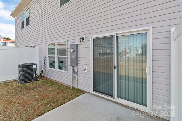 doorway to property with central AC and fence