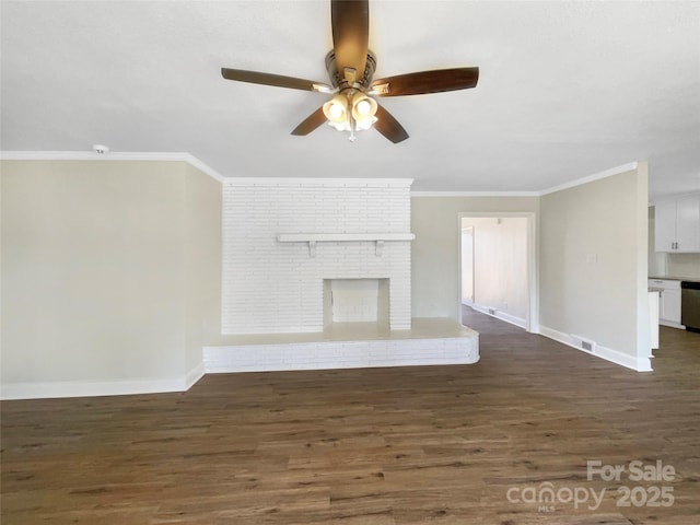 unfurnished living room featuring crown molding, a brick fireplace, dark wood finished floors, and baseboards