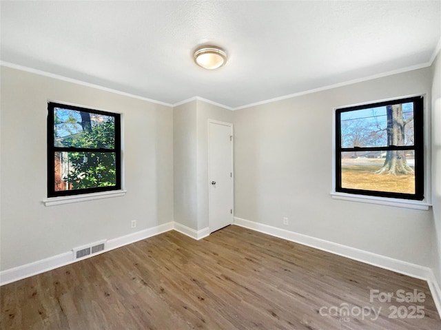 unfurnished room featuring visible vents, crown molding, baseboards, and wood finished floors