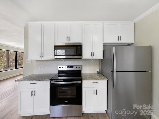 kitchen featuring appliances with stainless steel finishes, white cabinetry, decorative backsplash, and light stone countertops