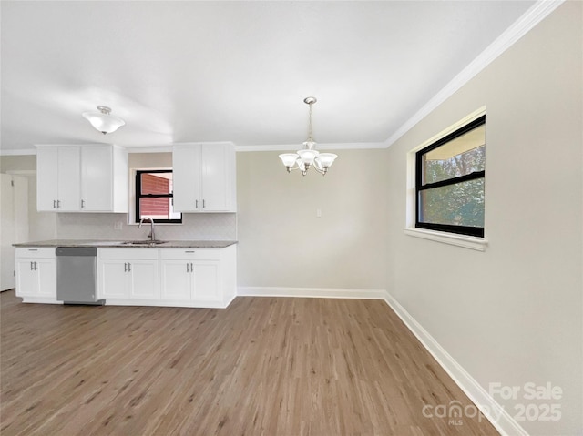 kitchen with a sink, baseboards, white cabinets, dishwasher, and crown molding