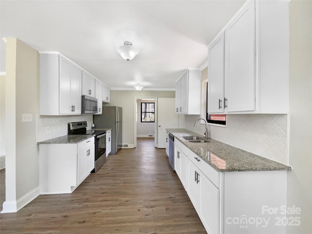 kitchen with wood finished floors, appliances with stainless steel finishes, a sink, and white cabinetry