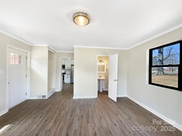 interior space featuring baseboards, crown molding, visible vents, and wood finished floors