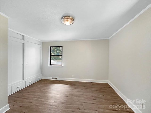 unfurnished bedroom featuring baseboards, visible vents, wood finished floors, crown molding, and a closet