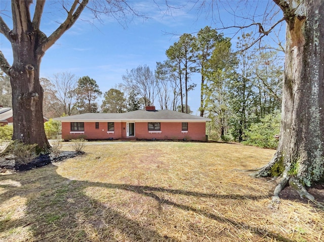 ranch-style home featuring brick siding, a chimney, and a front lawn