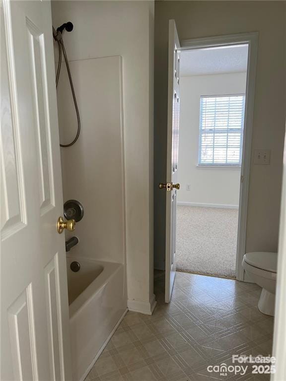 bathroom with baseboards, toilet, and bathtub / shower combination