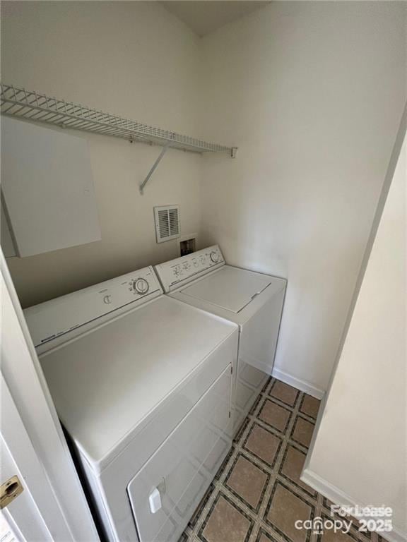 clothes washing area featuring washer and clothes dryer, visible vents, laundry area, and baseboards