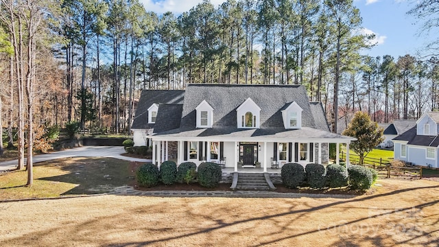 cape cod house featuring a porch, a front lawn, and fence