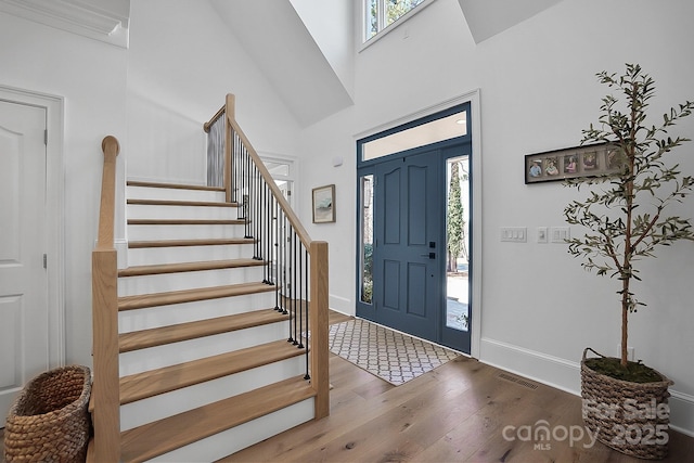 foyer with a wealth of natural light, visible vents, stairs, and wood finished floors