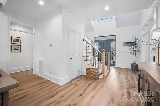 entrance foyer featuring visible vents, light wood-style flooring, stairway, crown molding, and baseboards