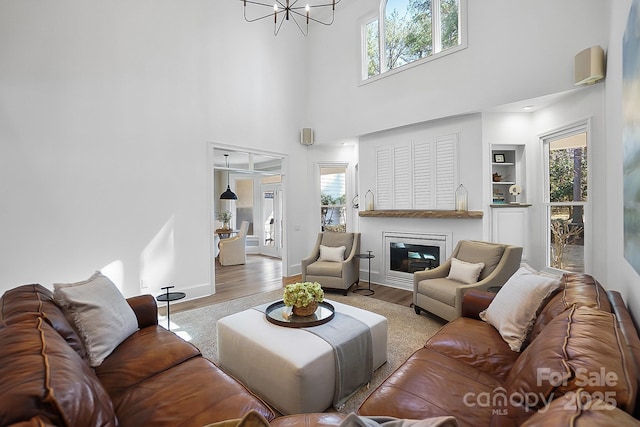 living room with a wealth of natural light, baseboards, a glass covered fireplace, and wood finished floors