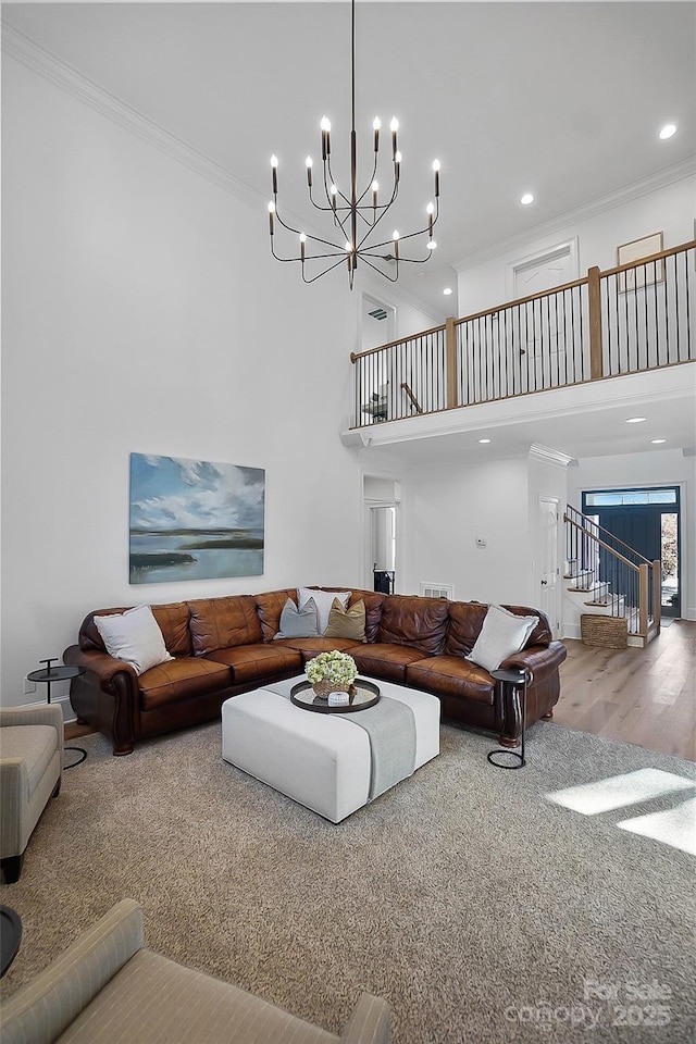 living area with wood finished floors, recessed lighting, stairway, a high ceiling, and crown molding