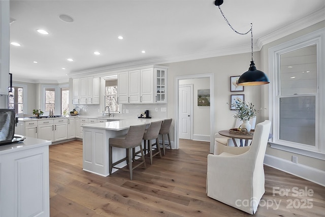 kitchen featuring a sink, a kitchen breakfast bar, white cabinets, and crown molding