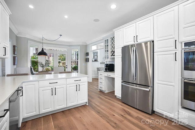 kitchen with light countertops, appliances with stainless steel finishes, crown molding, and white cabinetry