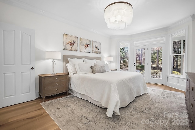 bedroom with ornamental molding, wood finished floors, an inviting chandelier, and access to outside