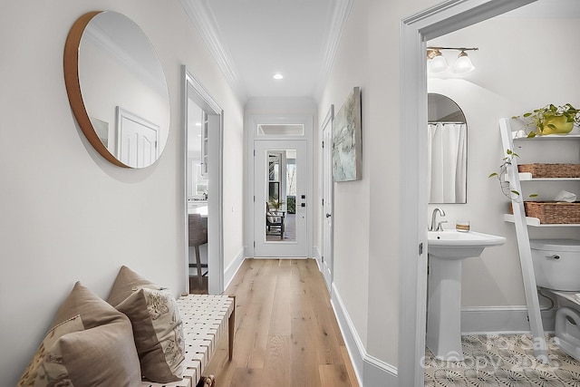 hallway featuring baseboards, light wood-style flooring, and crown molding