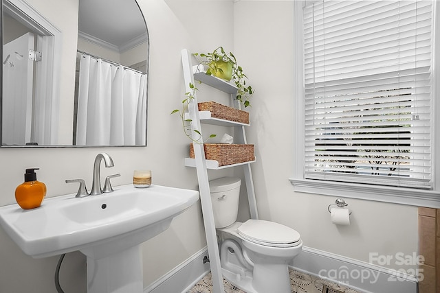 bathroom featuring ornamental molding, toilet, baseboards, and a sink