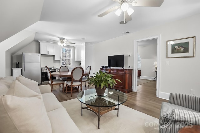 living area with baseboards, visible vents, a ceiling fan, and light wood-style floors