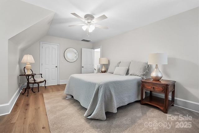 bedroom featuring lofted ceiling, wood finished floors, visible vents, and baseboards