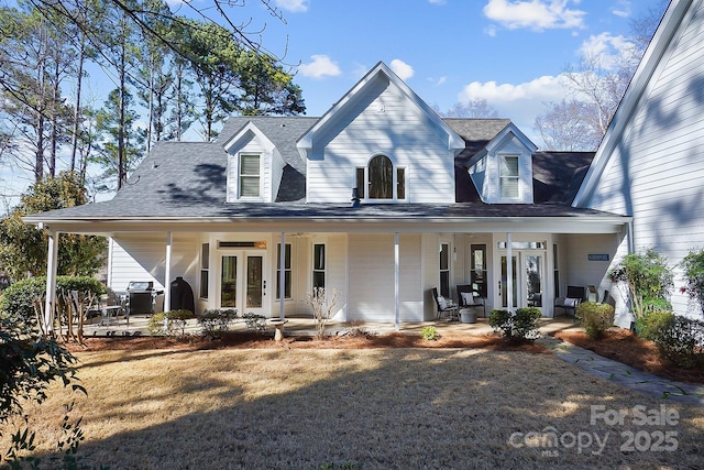 view of front of home with covered porch, a front lawn, and a shingled roof