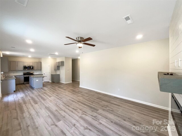 kitchen with appliances with stainless steel finishes, wood finished floors, visible vents, and baseboards