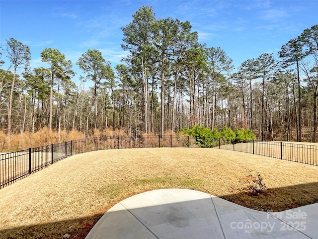 view of yard with a patio area, a fenced backyard, and a forest view