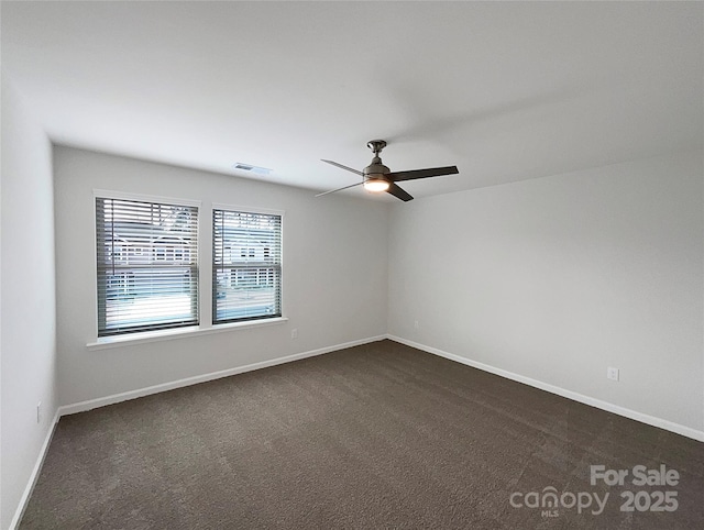 empty room featuring dark colored carpet, visible vents, ceiling fan, and baseboards