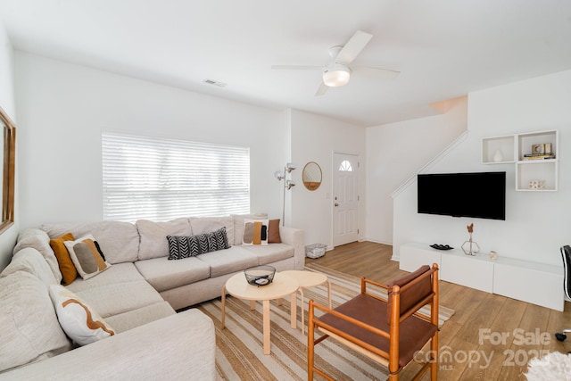 living room with a ceiling fan, visible vents, and light wood-type flooring