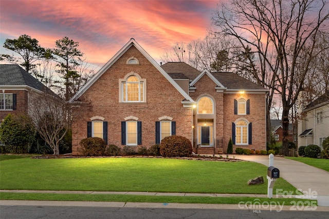 view of front of house with brick siding, roof with shingles, concrete driveway, and a front lawn