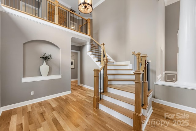 staircase with wood finished floors, baseboards, and ornamental molding