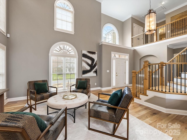 living area with stairs, light wood-style floors, baseboards, and ornamental molding