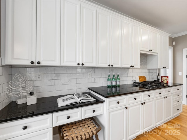 kitchen featuring gas cooktop, tasteful backsplash, white cabinets, and ornamental molding