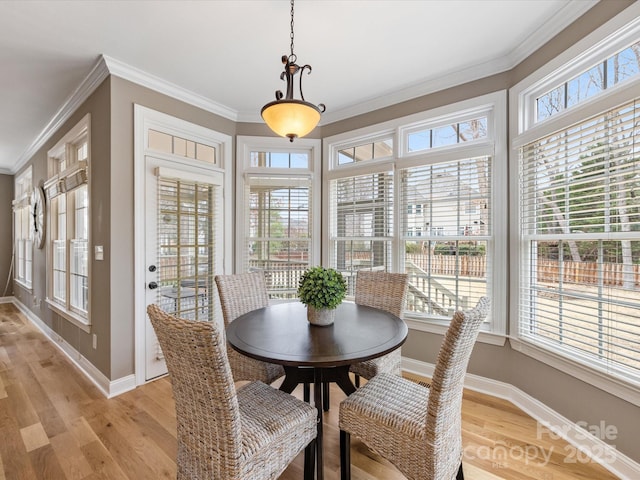 dining space with baseboards, light wood finished floors, and ornamental molding