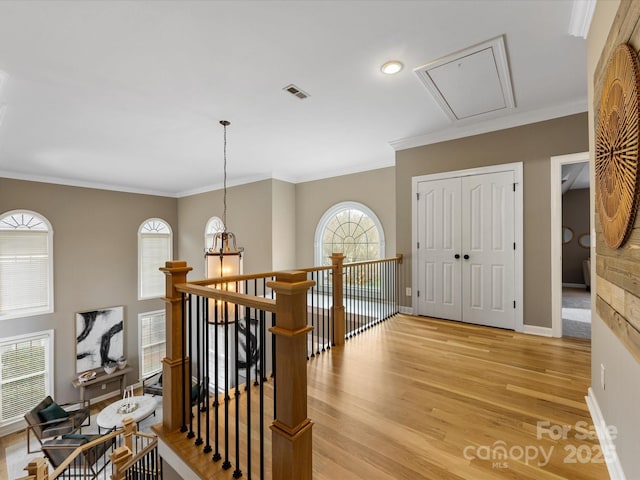 corridor featuring visible vents, an upstairs landing, light wood-style floors, crown molding, and baseboards