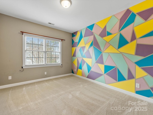 spare room with an accent wall, baseboards, visible vents, and carpet floors