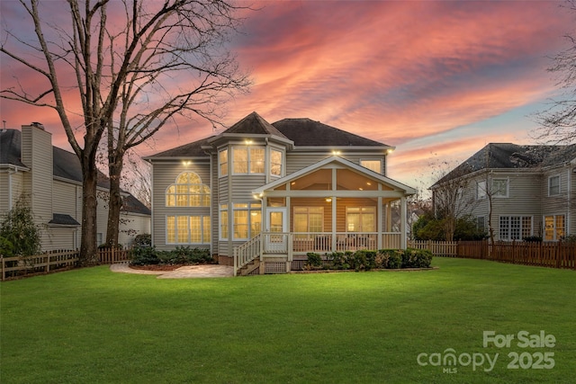 back of house with a lawn, fence, and a sunroom